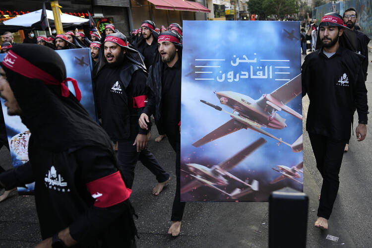 Members of Iranian-backed Hezbollah group walk barefoot as they carry a poster showing Hezbollah drones that read, in Arabic: "We are coming," during the holy day of Ashoura, which commemorates the 7th century martyrdom of the Prophet Muhammad's grandson Hussein, in the southern suburb of Beirut, Lebanon, Tuesday, Aug. 9, 2022. (AP Photo/Hussein Malla, File)