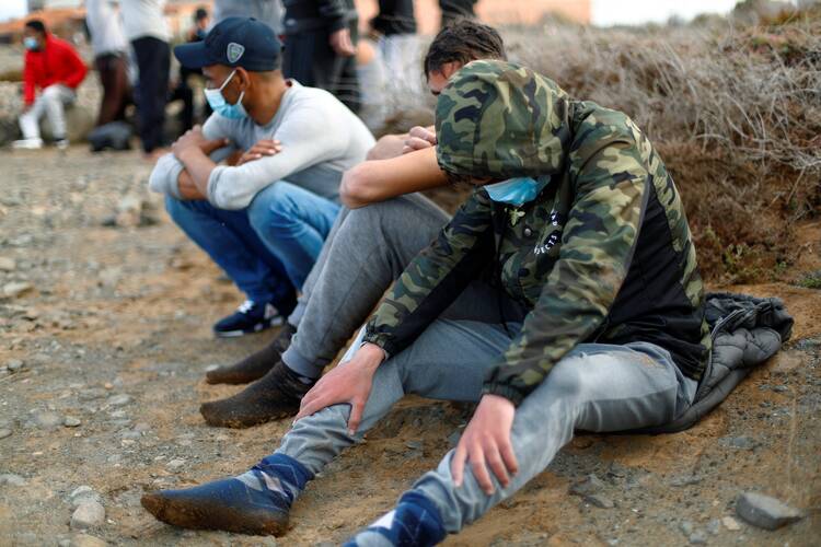 Resting at Castillo del Romeral beach after dozens of migrants arrived on Spain's Gran Canaria Island on Oct. 16, 2020, during the Covid-19 pandemic. (CNS photo/Borja Suarez, Reuters)