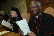 Cardinal Peter Turkson and Orthodox Metropolitan John of Pergamon holds copies of Pope Francis' encyclical on environment before news conference at Vatican.