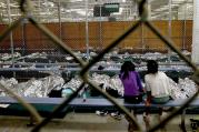 Two young girls watch a World Cup soccer match in a holding area where hundreds of mostly Central American immigrant children are being processed in Nogales, Az., on June 18.