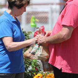 A volunteer in a blue shirt hands a plastic bag of potatoes to a person in need at a food pantry in July 2021.