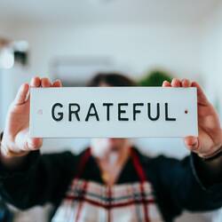 person holding white and black 'grateful' card